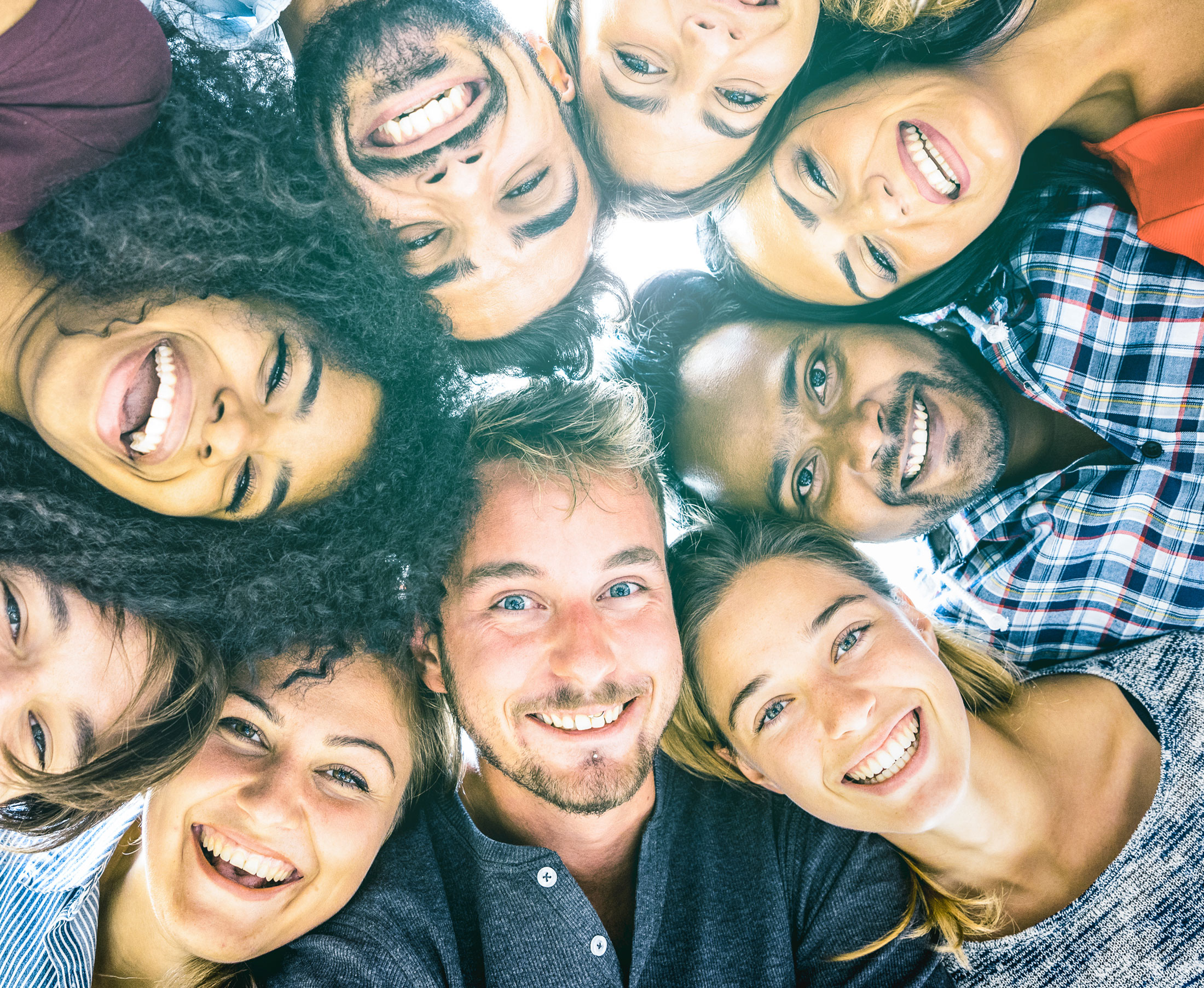 A group of people smiling together in a circle.