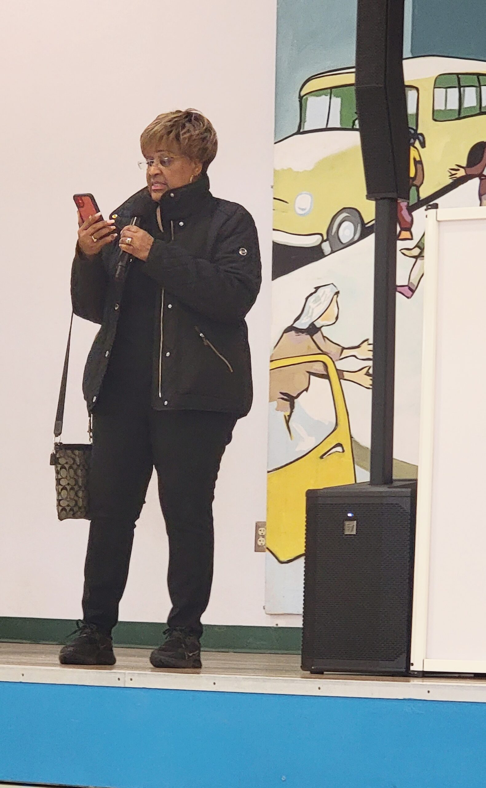 A woman standing on stage with a cell phone.