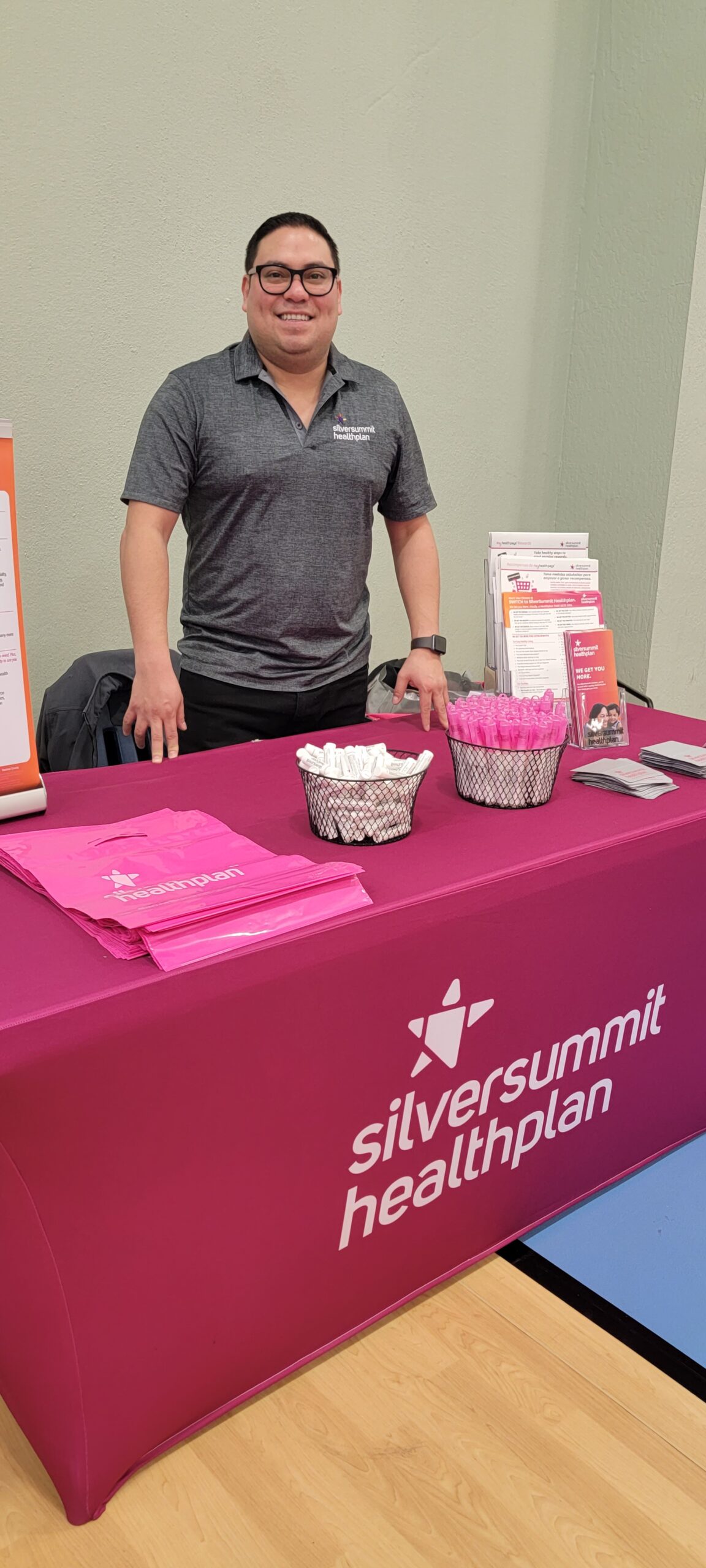 A man standing in front of a table with a silver summit healthcare plan sign.