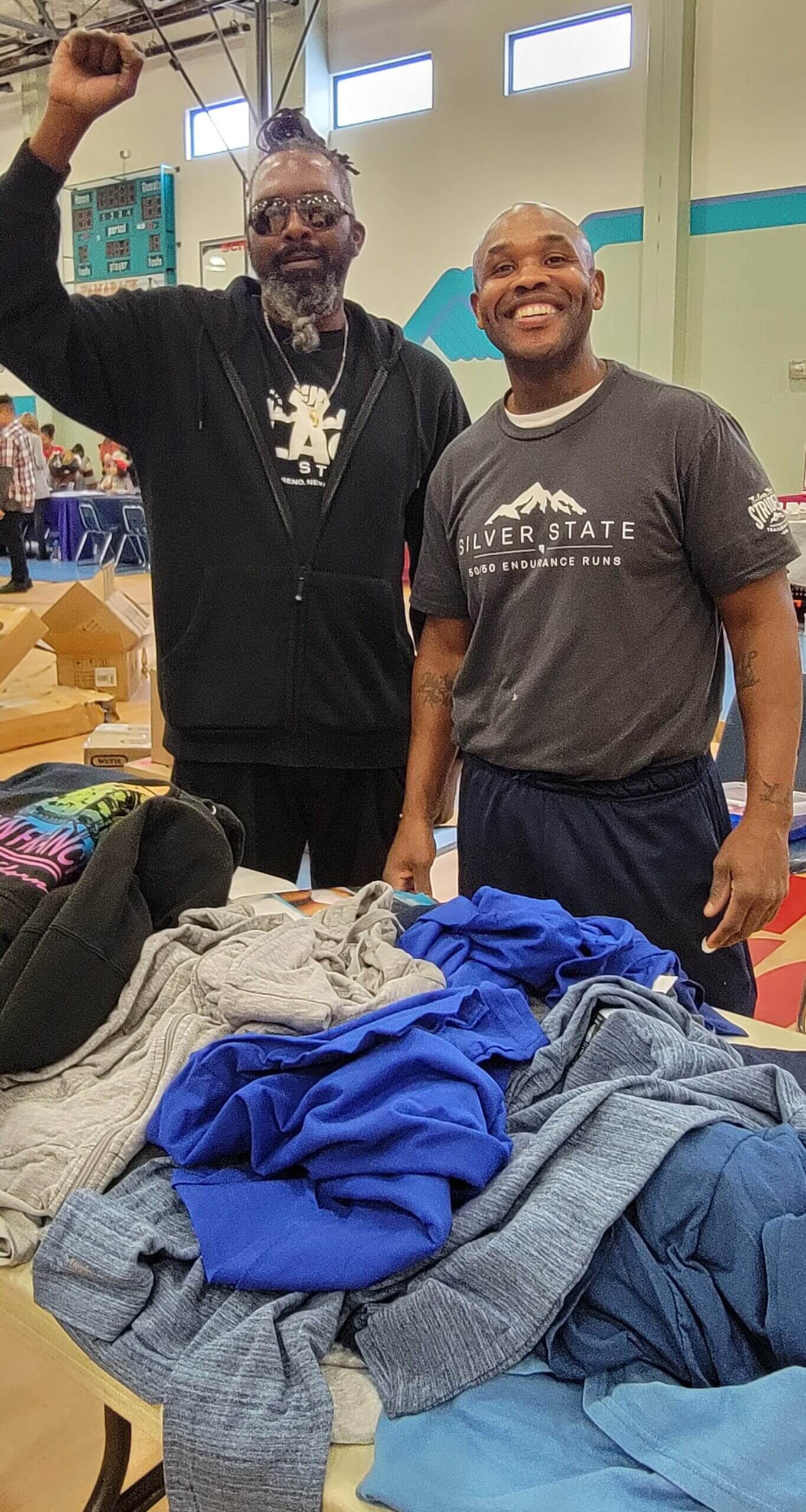 Two men standing next to a table full of clothes.
